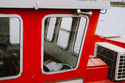 a red and white boat with windows and air conditioner