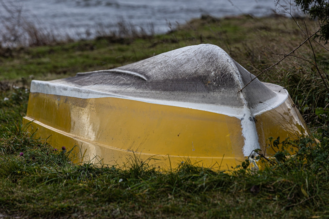 a yellow boat sitting on top of a lush green field