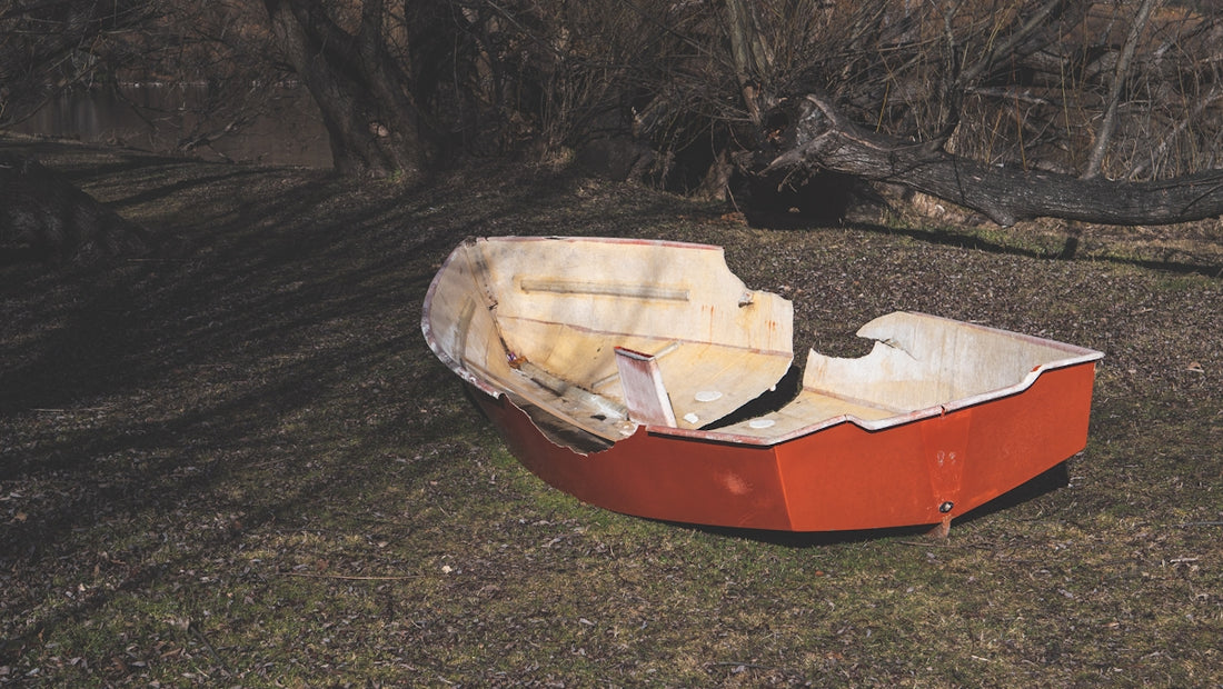 A red boat sitting on top of a grass covered field